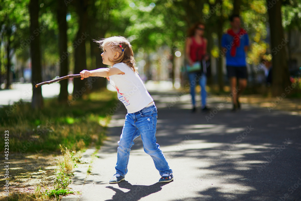 Obraz premium Adorable preschooler girl playing with a stick