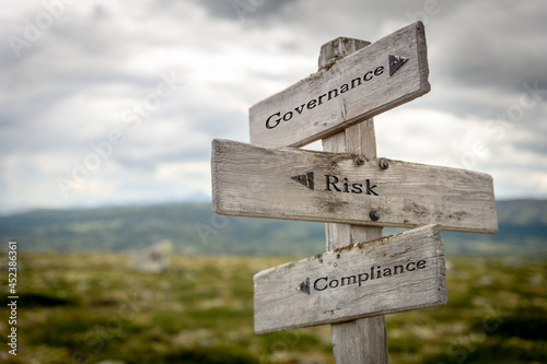 governance risk compliance text on wooden signpost outdoors in landscape scenery.