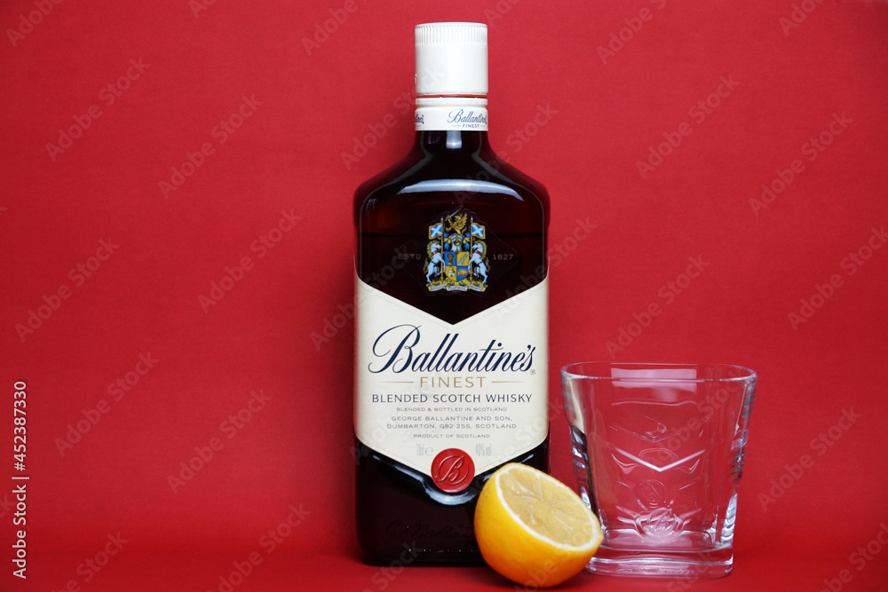 ballantine's whiskey bottle, glass and lemon on red background copy ...