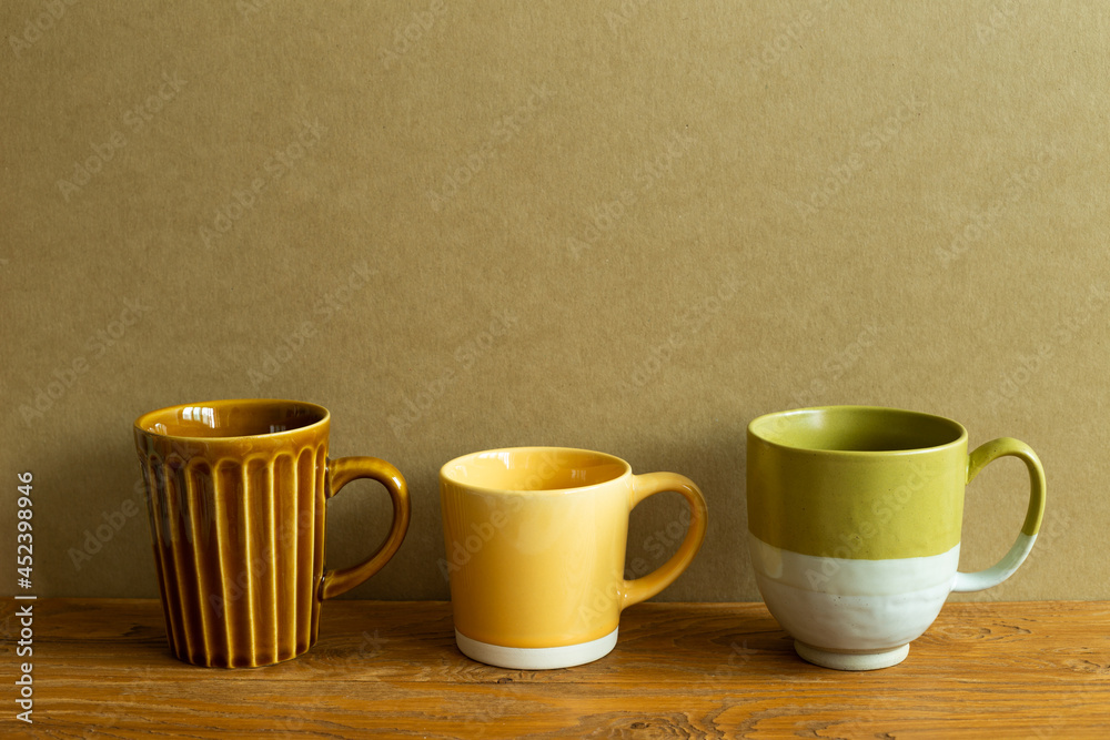 Mug cups on wooden table. brown wall background. copy space Mug cups on wooden table. brown wall background. copy space