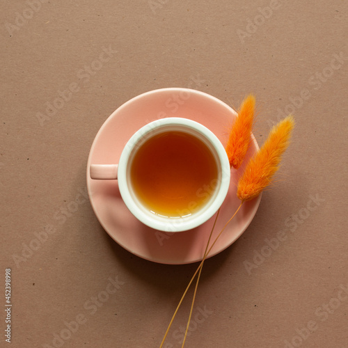 Cup of tea with dry flower on brown background. top view, copy space