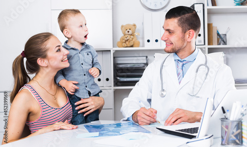 Portrait of man medical worker talking with young mother with child