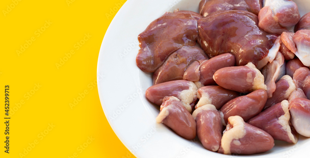 Mixed chicken entrails in white plate on yellow background.