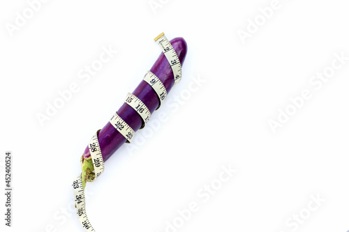 Long purple eggplant wrapped in measuring tape on white background.