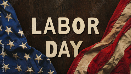 Vintage US American flag crumpled on worn wooden background with Labor Day text, celebrating American workers.