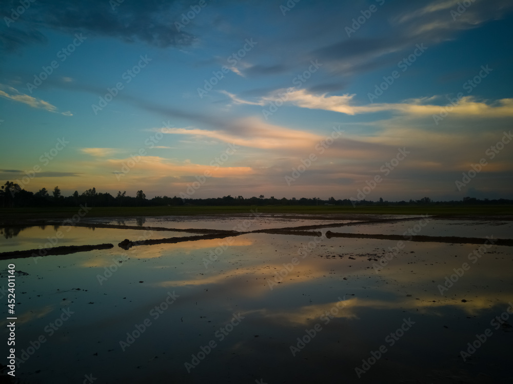 An Unique And Rare Natural Scenery Of Bangladesh With Colourful Clouds On Sky And The Reflection Of Colourful Clouds On Muddy Water Land. 