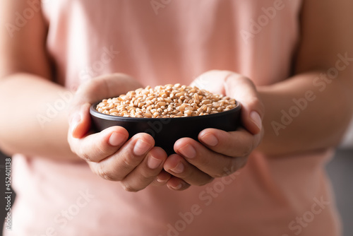 Wheat grain in a black bowl holding by woman hand