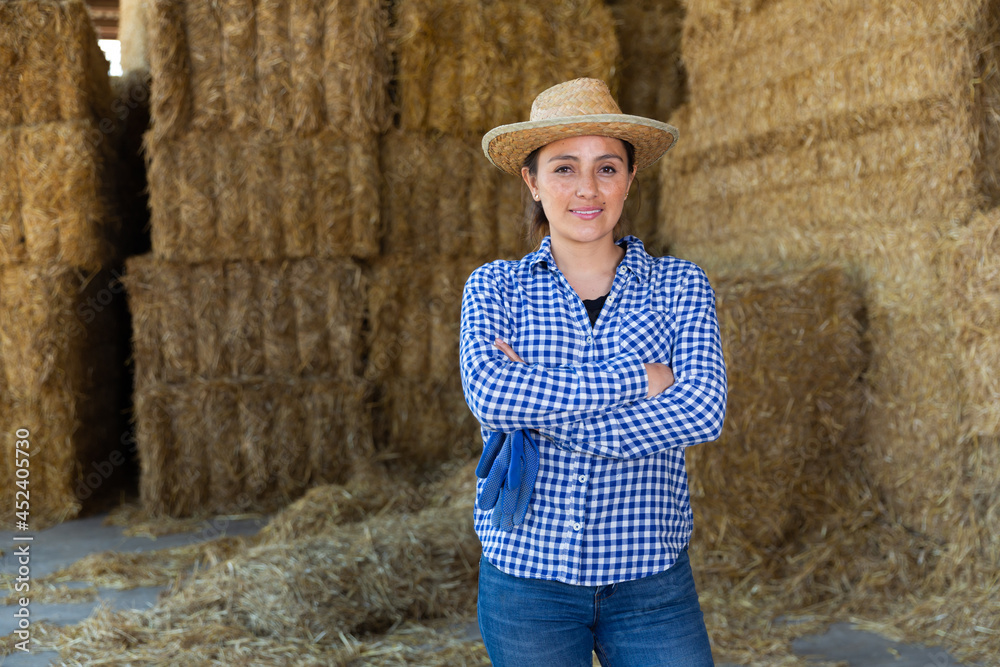 Portrait of cheerful latino american female farmer who is standing at the cow farm
