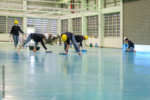 Construction workers are using trowel spreading epoxy putty for Self-leveling method of epoxy floor finishing work