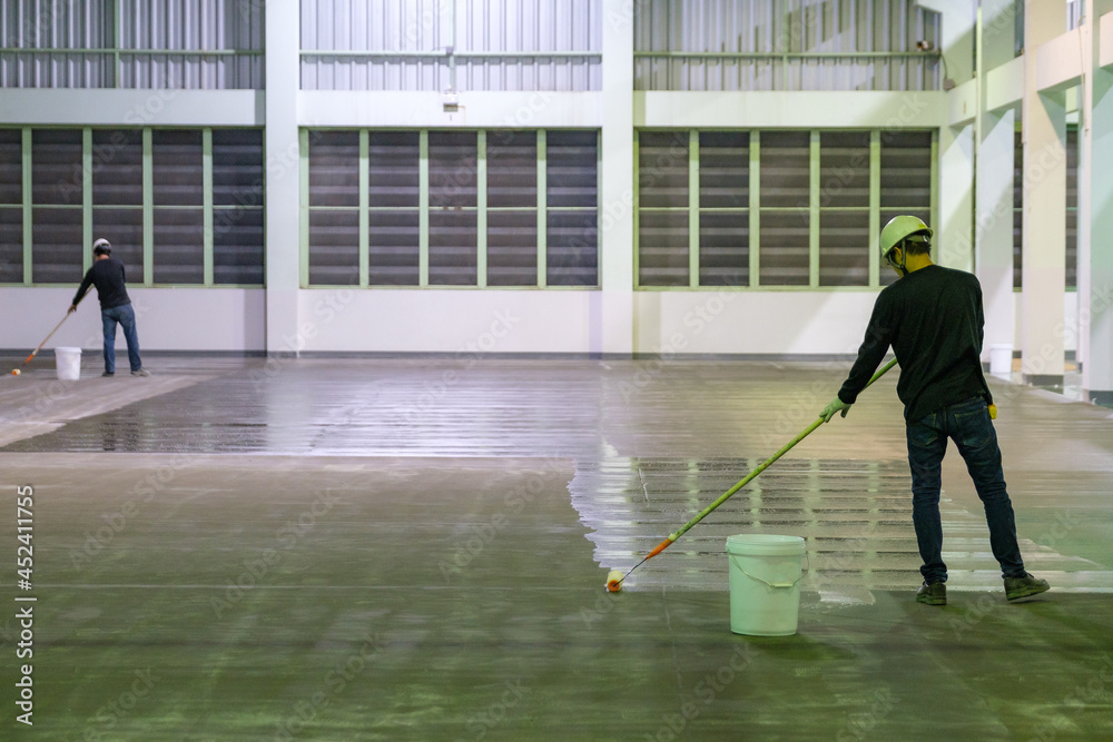 Construction worker using rollor spreading epoxy primer for Self