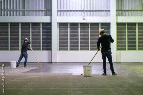 Construction worker using rollor spreading epoxy primer for Self-leveling method of epoxy floor finishing work