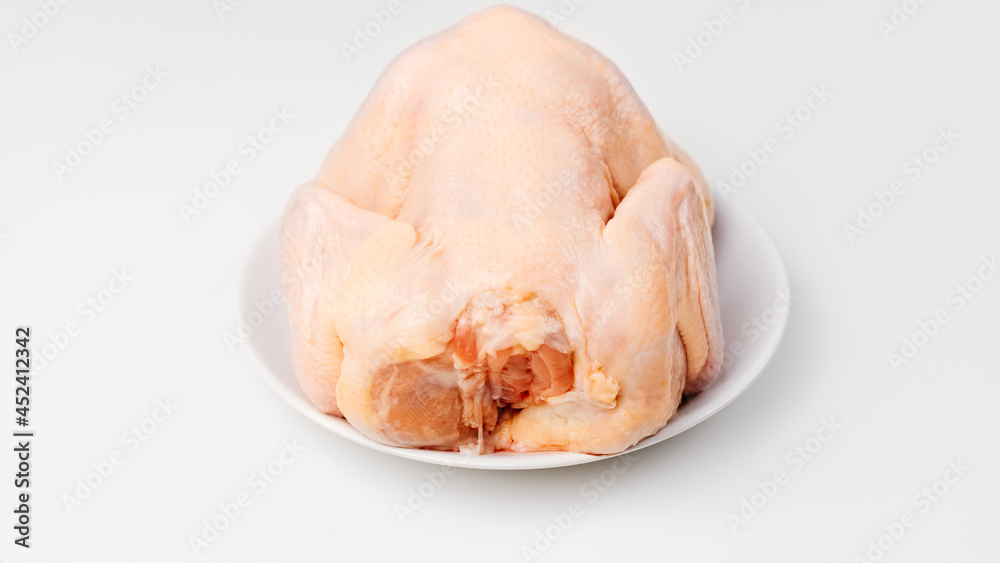 carcass of raw chicken on a white plate on a white background. carcass of raw chicken on a white plate on a white background.