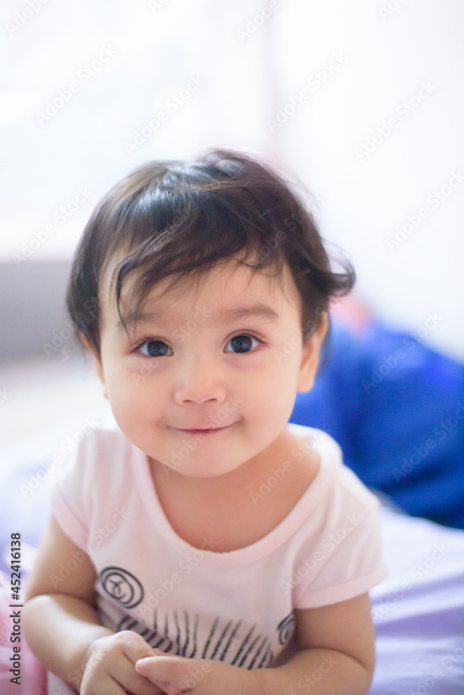 Portrait of a cute happy little Asian baby girl she sit on bed and look at camera, baby expression concept Portrait of a cute happy little Asian baby girl she sit on bed and look at camera, baby expression concept