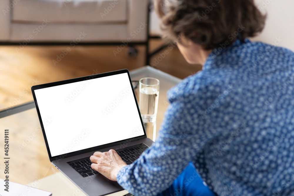 Views from back of aged business woman working while using laptop computer with blank screen Views from back of aged business woman working while using laptop computer with blank screen