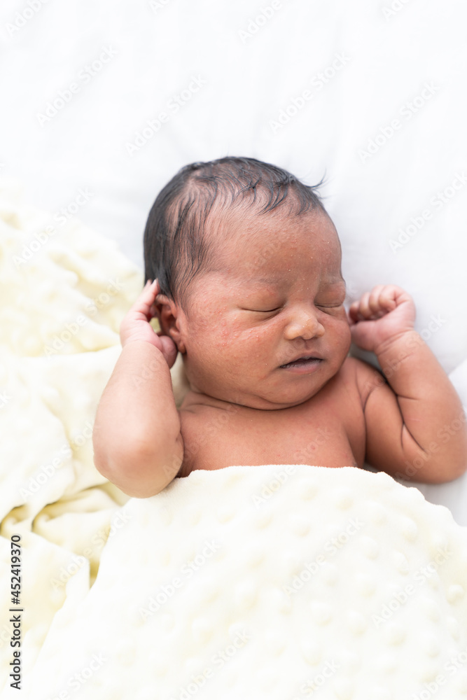 Top view of Newborn baby sleeping with blanket on white bed. Infant lying on white bed. African