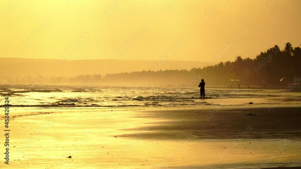 Silhouetted man fishing on a tropical beach in Vietnam at sunset. Silhouetted man fishing on a tropical beach in Vietnam at sunset.
