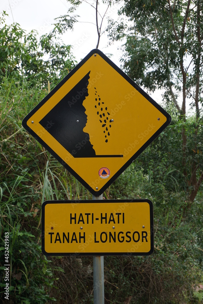 Yellow sign with a natural background. Hati-hati tanah longsor means beware of landslides