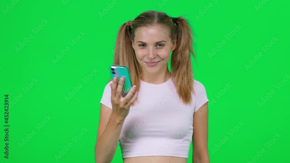Cheerful caucasian female holds a smartphone in her hands and shows it to the camera, beautiful female shares her emotions and shows her smartphone, chromakey template. Cheerful caucasian female holds a smartphone in her hands and shows it to the camera, beautiful female shares her emotions and shows her smartphone, chromakey template.