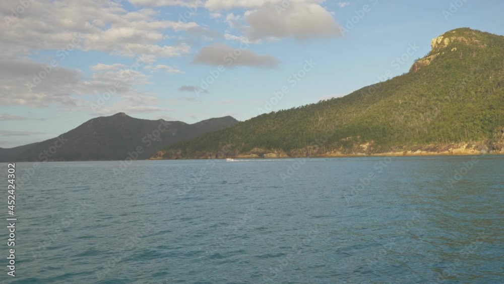 Distant View Of A Motorboat Speeding Across Hook Island Passage In Whitsundays, QLD With Rugged Inlet In Background. wide shot Distant View Of A Motorboat Speeding Across Hook Island Passage In Whitsundays, QLD With Rugged Inlet In Background. wide shot