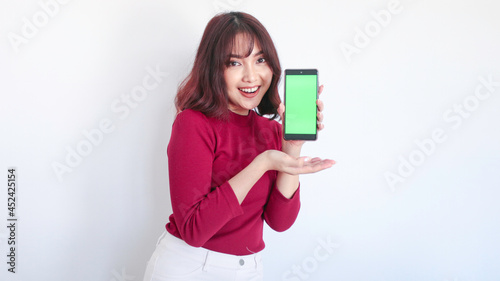 Shock Asian beautiful girl point on green screen phone in white background