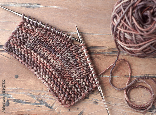Wool yarn ball and knitting needles on the wooden backgrounds.