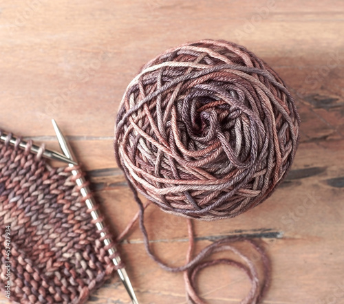Wool yarn ball and knitting needles on the wooden backgrounds.