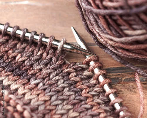 Wool yarn and knitting needles on the wooden backgrounds. Closeup.