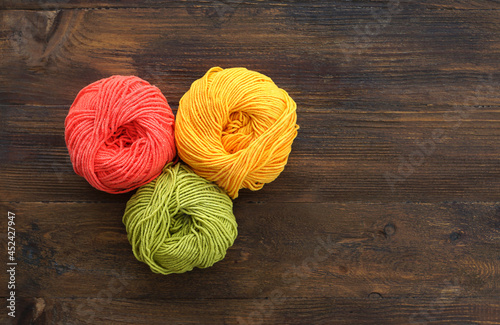 Three cotton yarn balls on wooden background. Copy space.