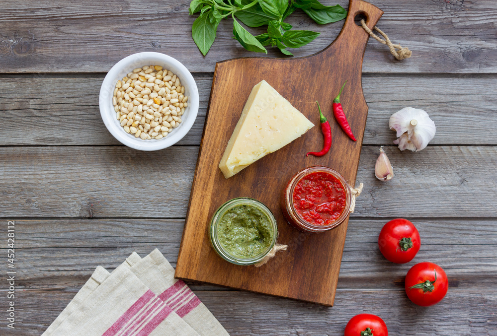 Two glass jars with red pesto and basil pesto. National kitchen. Healthy eating. Vegetarian food. Two glass jars with red pesto and basil pesto. National kitchen. Healthy eating. Vegetarian food.