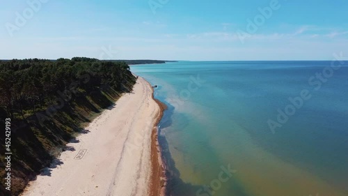 Flying Over Coastline Baltic Sea Jurkalne Seashore Bluffs Near Pavilosta Latvia and Landslides With an Overgrown, Rippling Cave Dotted Cliff and Pebbles. Aerial Dron View. Camera Moves Forward photo