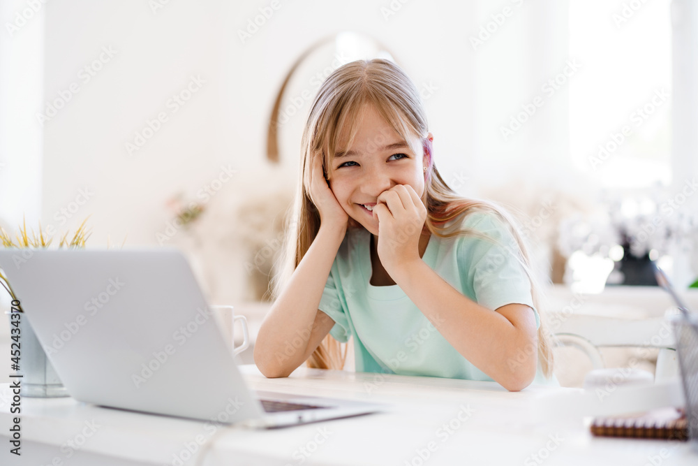 Happy little girl pupil using laptop at home Happy little girl pupil using laptop at home
