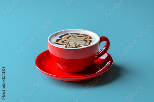Latte coffee in red mug decorated with caramel and chocolate motifs. put a glass on the blue background