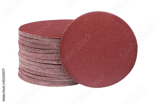 Red round sandpaper disc stands vertically next to the sander disc stack. Sanding disc for sander grits
 photo