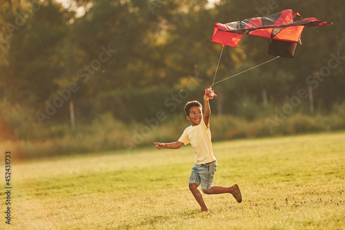 Running with red kite. African american kid have fun in the field at summer daytime #452438733