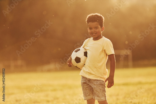 Illuminated by sunlight. African american kid have fun in the field at summer daytime © standret