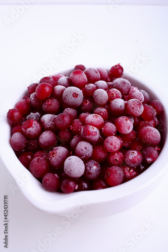 Frozen cranberry in white bowl on white background. Selective focus. Close up of frozen cranberries.