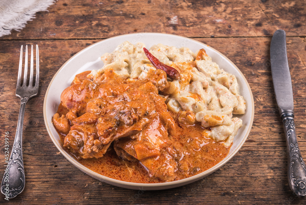 Chicken paprikash with gnocchi, portion of stewed chicken with hungarian garnish, dumplings on a plate, close-up, rustic style Chicken paprikash with gnocchi, portion of stewed chicken with hungarian garnish, dumplings on a plate, close-up, rustic style