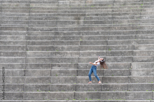 Happy woman listening to music and dancing alone on the stairs of a grandstand.