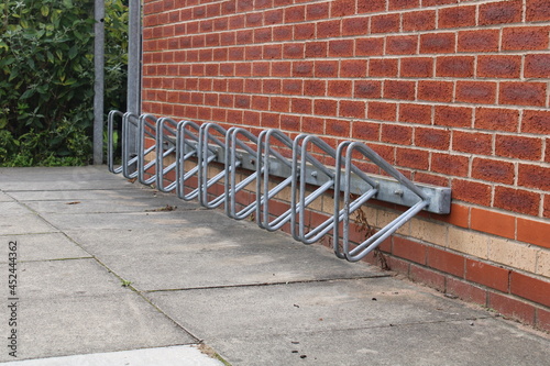 Empty bike rack, parking for bicycles against a red brick wall