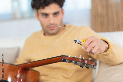 a man changes guitar strings photo