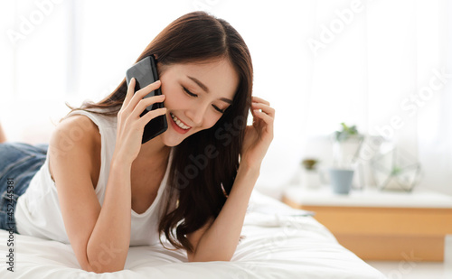 Portrait of smiling happy beautiful asian woman relaxing using digital technology smartphone.Young asian girl call and talk with friend at home