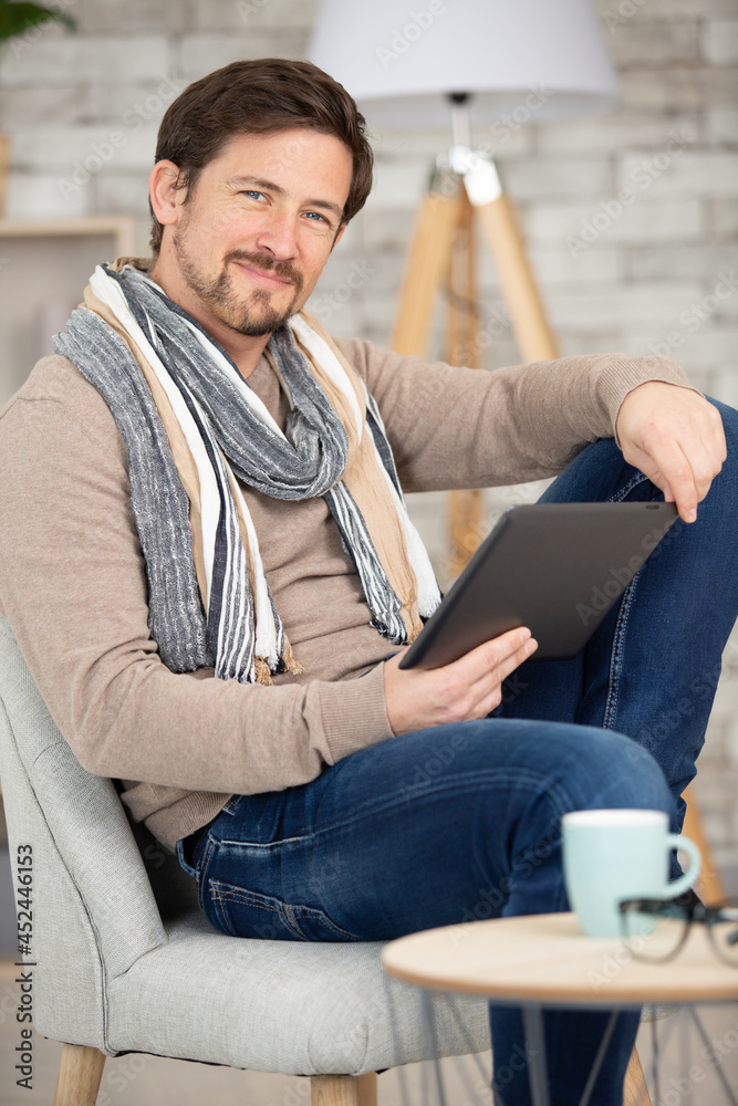 happy man relaxing on sofa with digital tablet