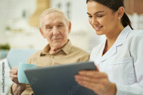 Nurse and senior citizen looking at tablet screen at home © Friends Stock