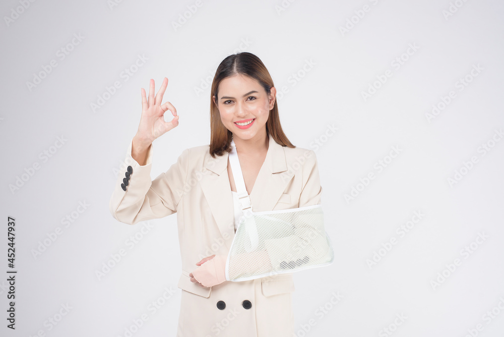 Portrait of young woman with an injured arm in a sling over white background in studio.. Portrait of young woman with an injured arm in a sling over white background in studio..