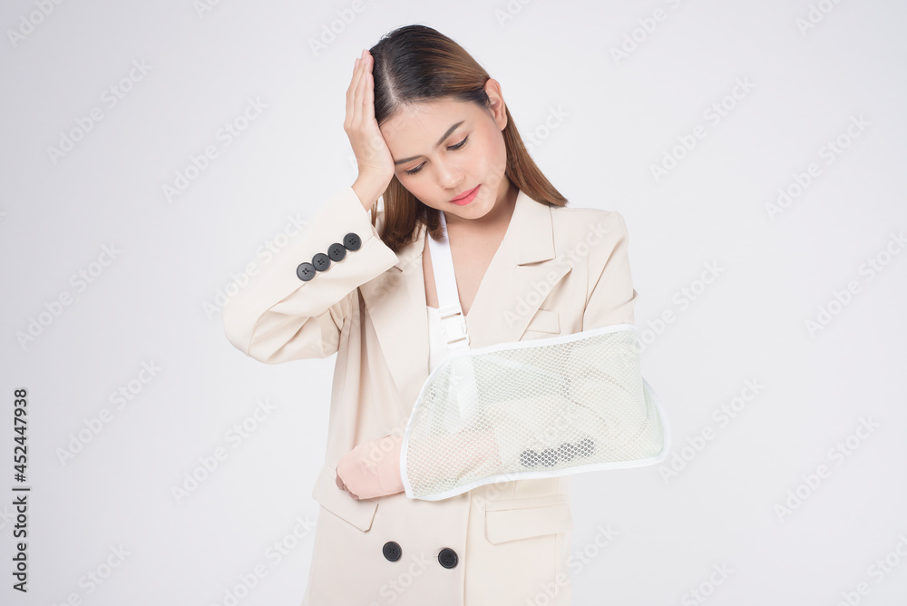 Portrait of young woman with an injured arm in a sling over white background in studio.. Portrait of young woman with an injured arm in a sling over white background in studio..