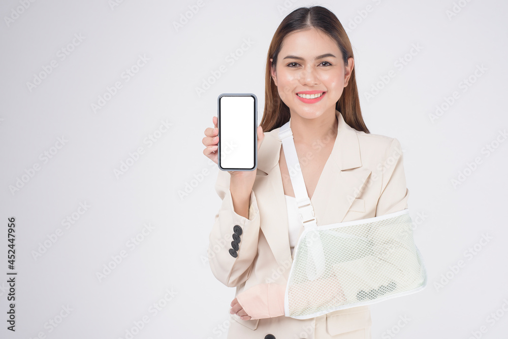 Portrait of young woman with an injured arm in a sling over white background in studio.. Portrait of young woman with an injured arm in a sling over white background in studio..