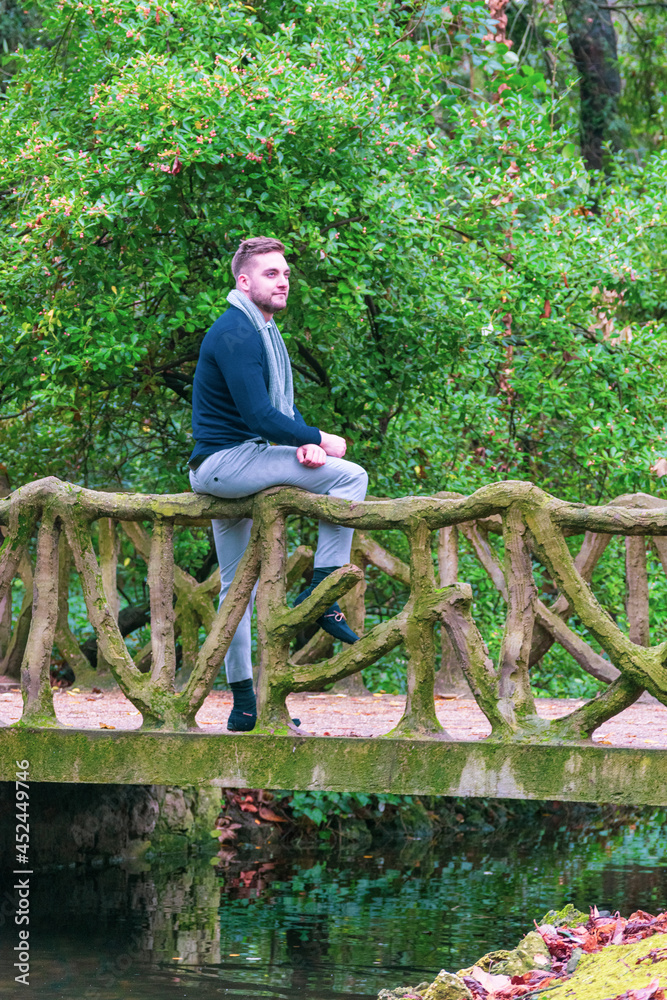 young man sitting on bridge with stone railing young man sitting on bridge with stone railing