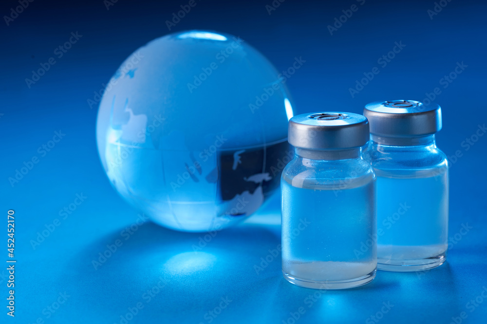 vaccine bottle and globe on blue background vaccine bottle and globe on blue background