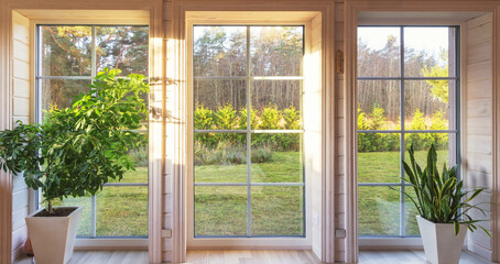 Bright interior of the room in wooden house with a large window overlooking the autumn courtyard. Home and garden, fall concept.