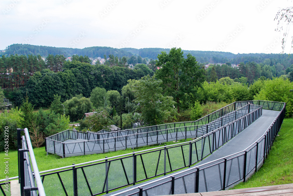 Pedestrian terrace, ramp - descent from the hill to the river. Metal structure on the hill.